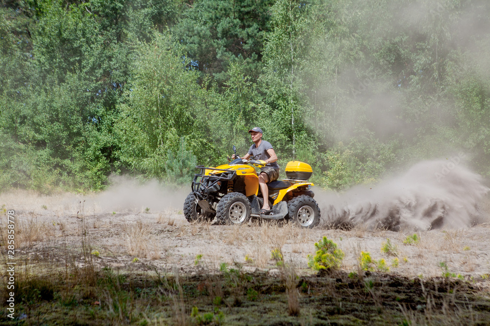 Man riding a yellow quad ATV all terrain vehicle on a sandy forest. Extreme sport motion, adventure, tourist attraction. Man riding a yellow quad ATV all terrain vehicle on a sandy forest. Extreme sport motion, adventure, tourist attraction.