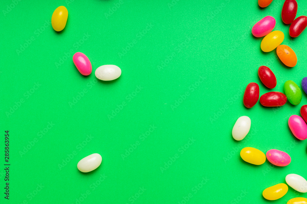 Fototapeta premium colourful jelly beans candies green background Top view