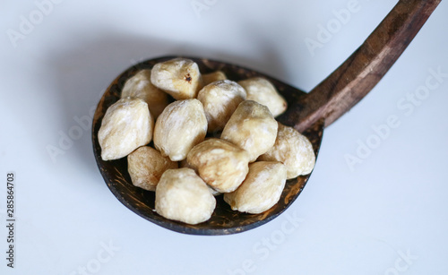 Candlenut on coconut shell ladle on white background.