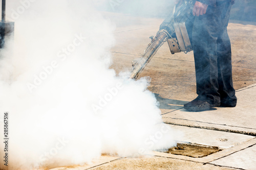 Man pointing smoke machine into manhole for pest control
