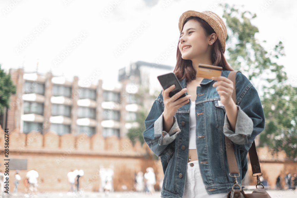 Smiling woman traveler in thapae gate landmark chiang mai thailand with backpack holding smartphone and credit card on holiday, relaxation concept, travel concept Smiling woman traveler in thapae gate landmark chiang mai thailand with backpack holding smartphone and credit card on holiday, relaxation concept, travel concept
