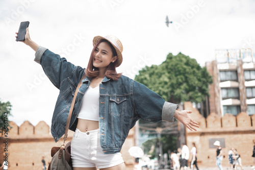 Smiling woman traveler in thapae gate landmark chiangmai thailand enjoy and arms raised with backpack on holiday, relaxation concept, travel concept photo