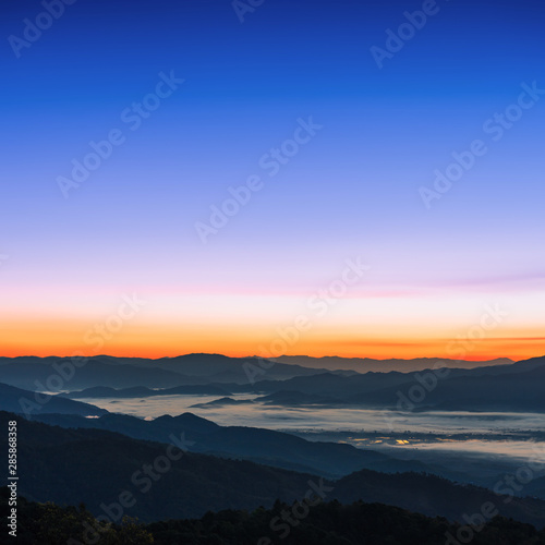 Beautiful foggy winter sunrise in mountains background.