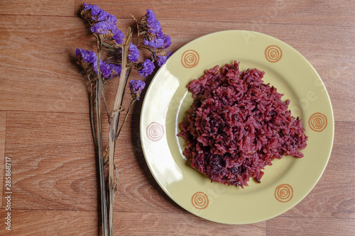 Close-up of riceberry rice in a plate on a wooden table background.