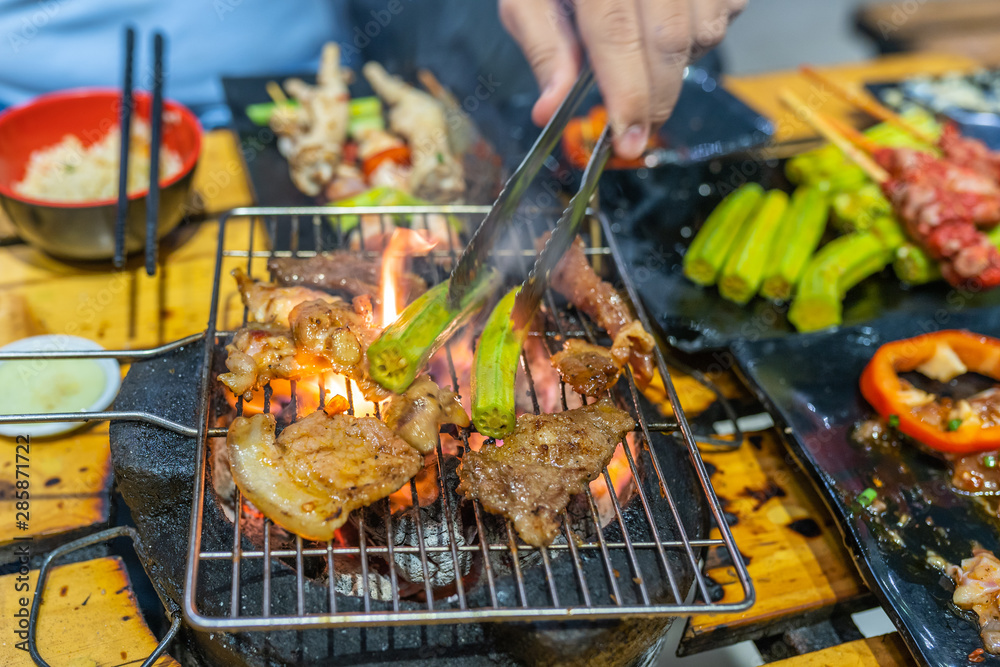 Barbecue meat and okra vegetables on flaming charcoal stove