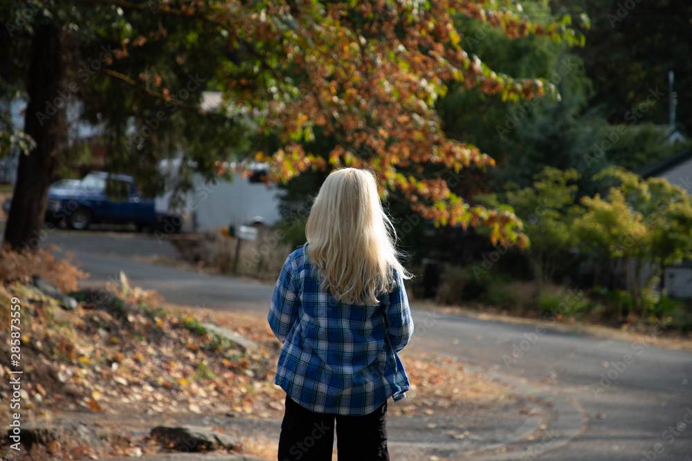 Fototapeta premium 10 year old boy with long blond hair walking down the street