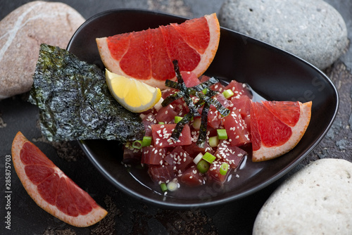 Black bowl with tuna fillet ceviche in grapefruit juice, studio shot, selective focus