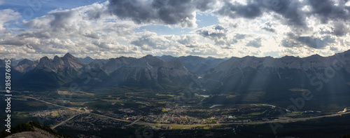 Beautiful Panoramic View of a small city in the Canadian Rocky Mountain Landscape during a cloudy and rainy day. Taken from Mt Lady MacDonald, Canmore, Alberta, Canada.