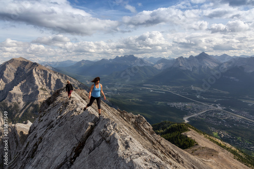 Adventurous Girl is hiking up a rocky mountain during a cloudy and rainy day. Taken from Mt Lady MacDonald, Canmore, Alberta, Canada. © edb3_16