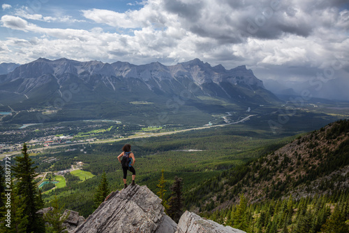 Adventurous Girl is hiking up a rocky mountain during a cloudy and rainy day. Taken from Mt Lady MacDonald, Canmore, Alberta, Canada. © edb3_16