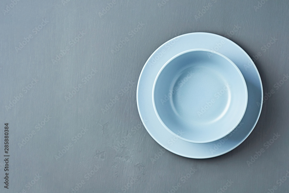 Group of modern empty ceramic plates of blue color lies on dark concrete background. Space for text. Top view Group of modern empty ceramic plates of blue color lies on dark concrete background. Space for text. Top view