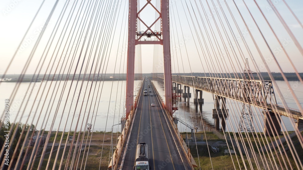 Obraz premium A smooth aerial flight, a flight over a bridge standing over a river on which cars ride. 4k.