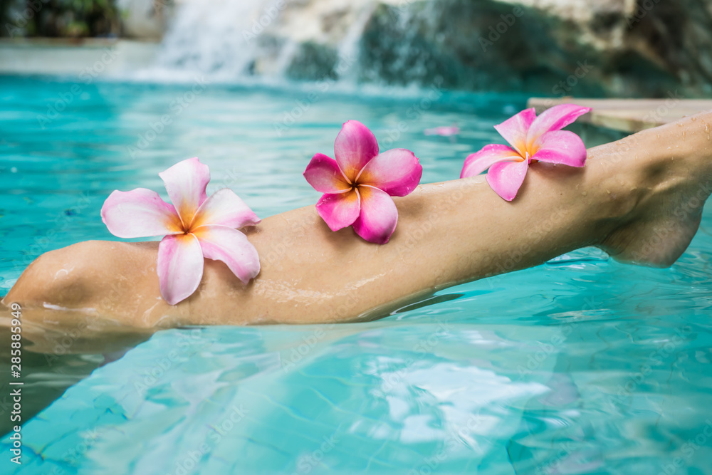 Woman Legs Beauty, Female Smooth Body, Foot Care, Hair Care. Beauty concept of woman legs, female smooth body, female foot in a pool with frangipani colors. Spa concept Woman Legs Beauty, Female Smooth Body, Foot Care, Hair Care. Beauty concept of woman legs, female smooth body, female foot in a pool with frangipani colors. Spa concept