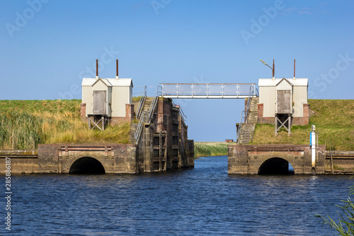 View of a small and old lock on a river flowing into the North Sea