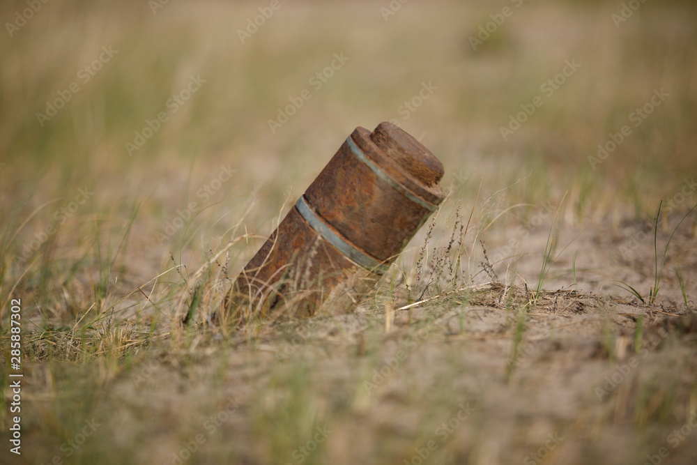 Rusty artillery shell sticks out of the ground Rusty artillery shell sticks out of the ground