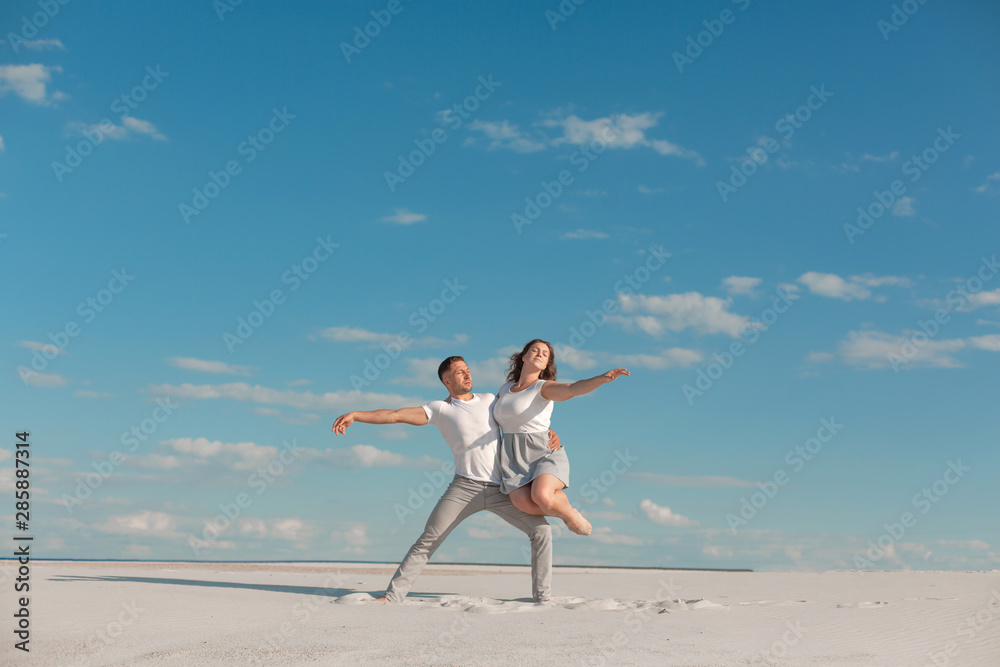 Romantic couple dancing in sand desert at blue sky background Romantic couple dancing in sand desert at blue sky background