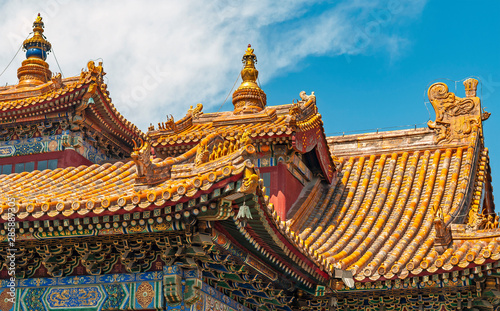 Rooftop architecture of the Yonghe temple or Lama temple on a sunny summer day in Beijing, China. Tibetan writing and translation: I honour the pearl inside the lotus flower.