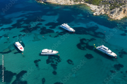 View from above, stunning aerial view of luxury yachts and boats floating on an emerald green bay of water in Sardinia. Maddalena Archipelago National Park, Sardinia, Italy...
