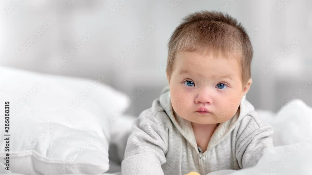 Portrait of pretty innocence little baby with blue eyes posing at white bedroom interior Portrait of pretty innocence little baby with blue eyes posing at white bedroom interior