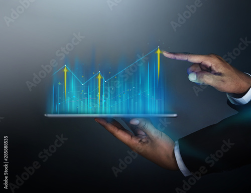 Technology, High Profit, Stock Market, Business Growth, Strategy Planing concept. Businessman in Suit Touching High Graphs and Charts Information on Digital Tablet