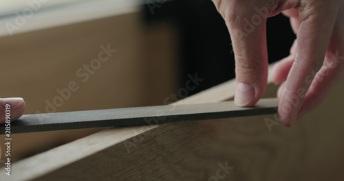 closeup man hand sandig oak board edge with file