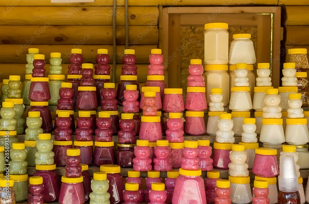 Fototapeta premium different honey in plastic cans stands on a wooden counter in the room