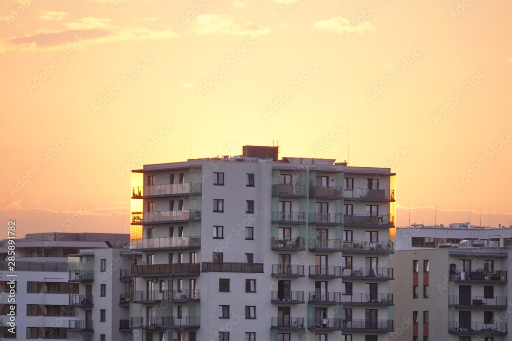 sunset light on a modern multi-storey building. the sky without clouds of different shades of red and orange.