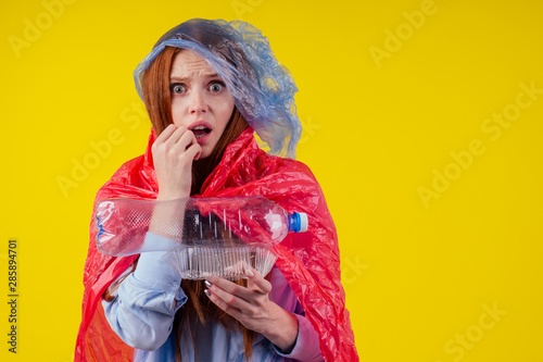 redhaired ginger european woman wear cloth full of plastic trash in yellow studio background.recycling ecology solution or fast fashion concept
