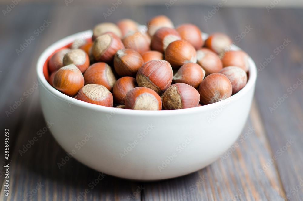 Hazelnuts in a white plate. Brown wooden background. Selective focus Hazelnuts in a white plate. Brown wooden background. Selective focus