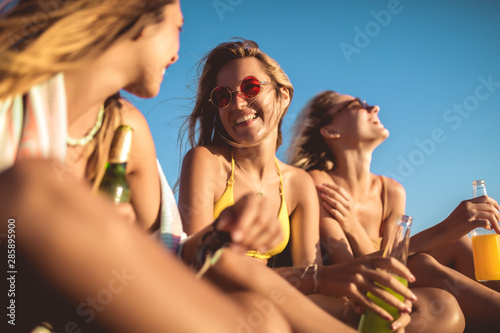 Happy young women sitting on the beach. Group of friends enjoying on beach holiday. © Mediteraneo