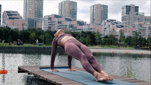 Young woman doing yoga exercises with city on background. purvottanasana photo