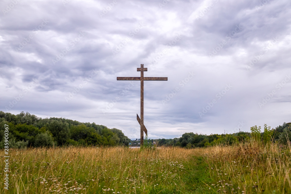 Big wooden eastern orthodox christianity cross in summer landscape
