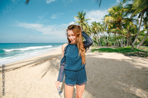 Cheerful young womanholding hair on the beach. Happy smiling girl enjoying the beach. Beautiful  tanned woman feeling refreshed during summer vacation.Summer mood photo