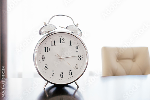 Old retro alarm clock on wooden table with pastel background. Time change concept