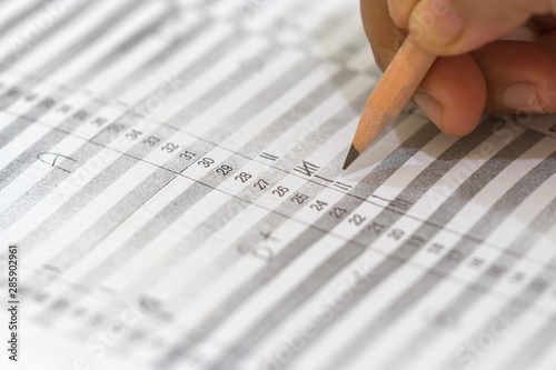 Concept of measurement and evaluation. Hand of teacher using pencil written text on paper of final grades for each course. The number of grade points student earned in given period of time of school.