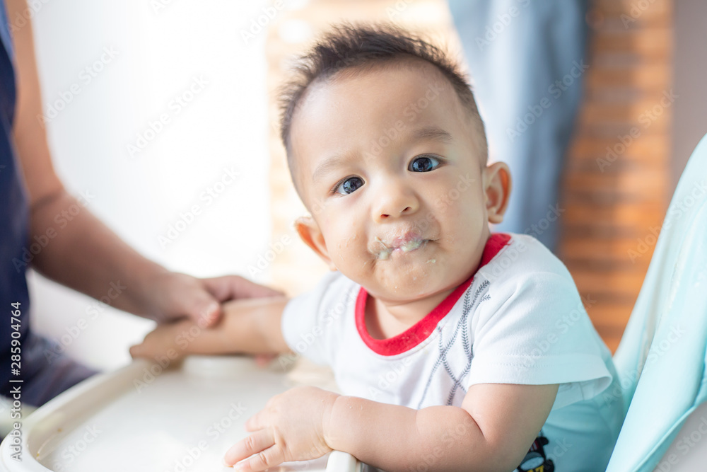 Asian baby child boy sitting on baby chair try to eating blend food Asian baby child boy sitting on baby chair try to eating blend food