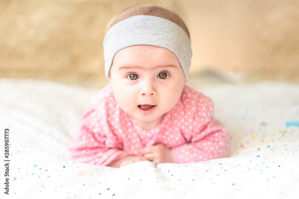 Adorable baby girl with grey headband looking towards camera and smiling. Health concept Adorable baby girl with grey headband looking towards camera and smiling. Health concept