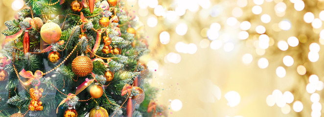 Christmas tree decorated with Golden balls and toy bears on a blurred, sparkling and fabulous fairy gold background with beautiful bokeh, copy space, banner format.