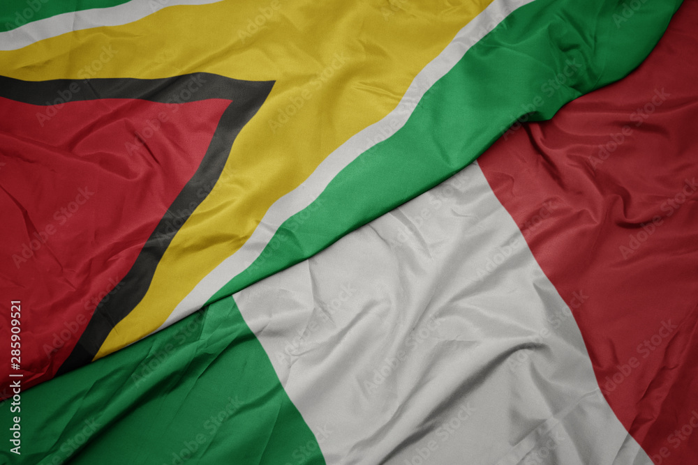 waving colorful flag of italy and national flag of guyana.