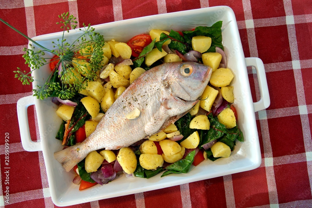 casserole with fresh gilthead sea bream with vegetable and herbs as top view. Raw dorado fish with spices and vegetables on the table. Diet vegetarian food. Dorado Royale Fish casserole with fresh gilthead sea bream with vegetable and herbs as top view. Raw dorado fish with spices and vegetables on the table. Diet vegetarian food. Dorado Royale Fish