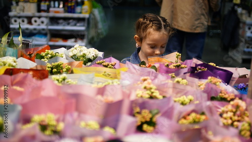 Portrait of cute little girl choosing flowers in supermarket