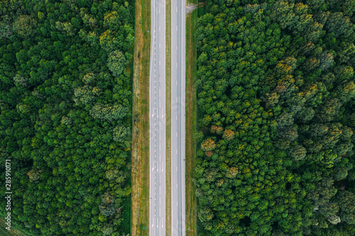 Aerial View Of Highway Road Through Green Forest Landscape In Summer. Top View Flat View Of Highway Motorway Freeway From High Attitude. Trip And Travel Concept