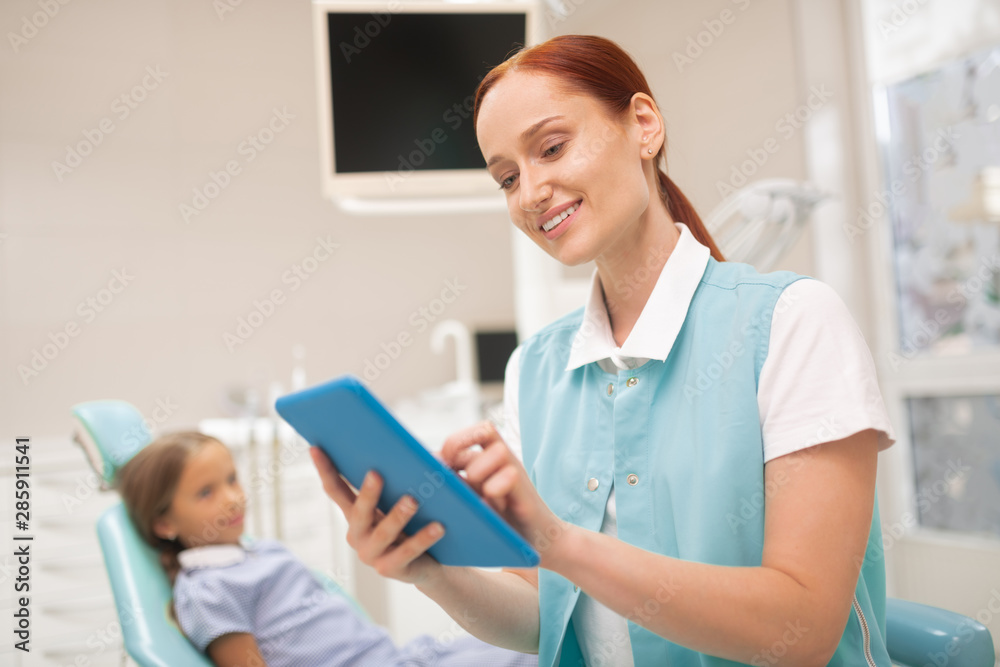 Obraz premium Child dentist smiling while studying clinical record