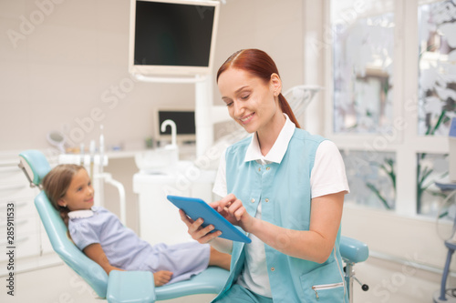Dentist smiling while filling information on tablet