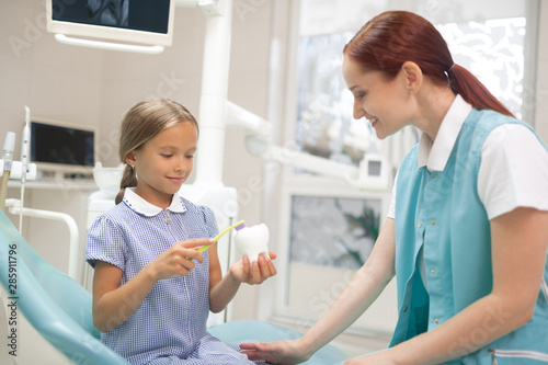 Doctor telling girl about importance of dental care