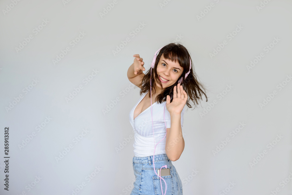 close up photo of a happy brunette with pink headphones in white blouse and denim skirt