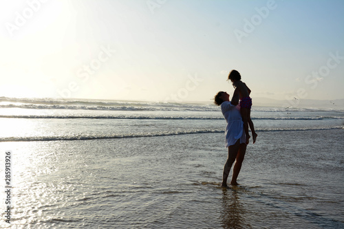 Loving my daughter. Mother raises her daughter up on a beautiful beach before sunset. The concept of the celebration, women's day © Nenad