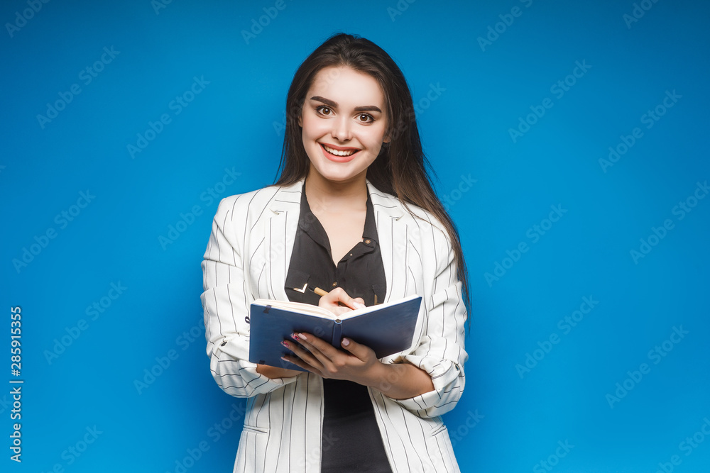 Portrait of elegant smart businesswoman wearing white jacket holding folder and smiling.