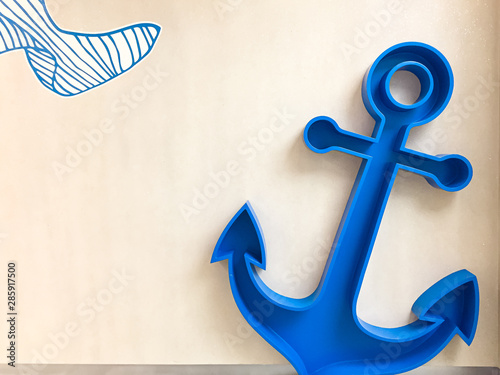 Big blue anchor for kid with wooden background.