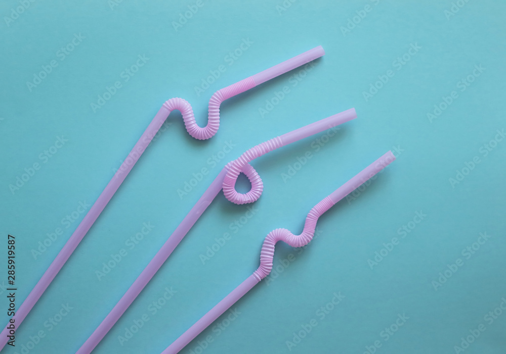 Pink plastic cocktail tubes with a flexible part, due to which they can be twisted into a knot or in a zigzag, on a blue background. Modern and trendy colors. Eco concept Pink plastic cocktail tubes with a flexible part, due to which they can be twisted into a knot or in a zigzag, on a blue background. Modern and trendy colors. Eco concept